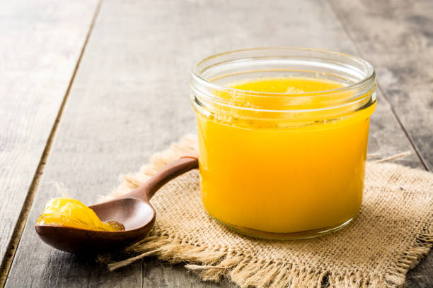 ghee or clarified butter in jar and wooden spoon on wooden table
