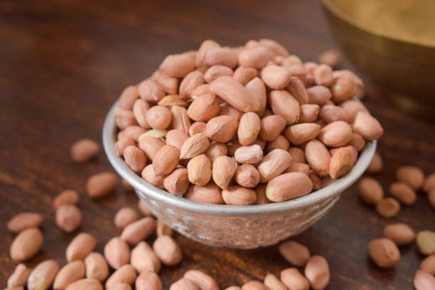 peeled peanuts in a silver bowl on wooden old table. rustic style